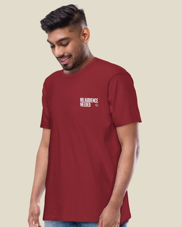 Close view of the NO AUDIENCE NEEDED statement printed on the left chest of the Men's fit shirt, in Brick Red.
